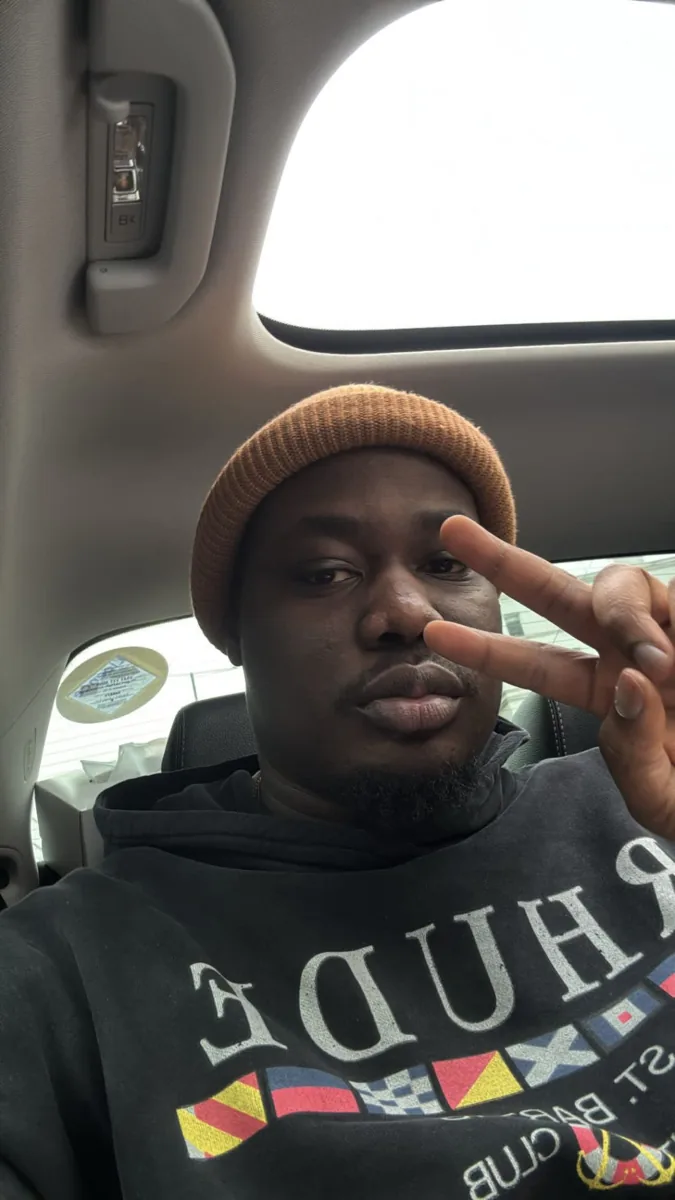 Mayowa in a brown beanie, making a peace sign